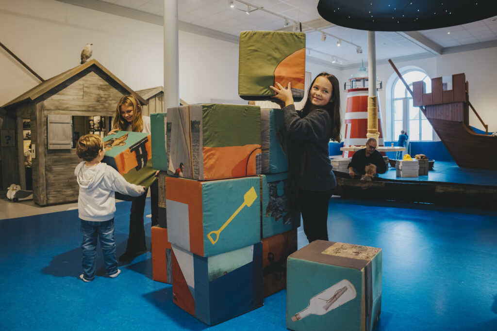 Barn i olika åldrar som leker med fyrkantiga kuddar av tyg.