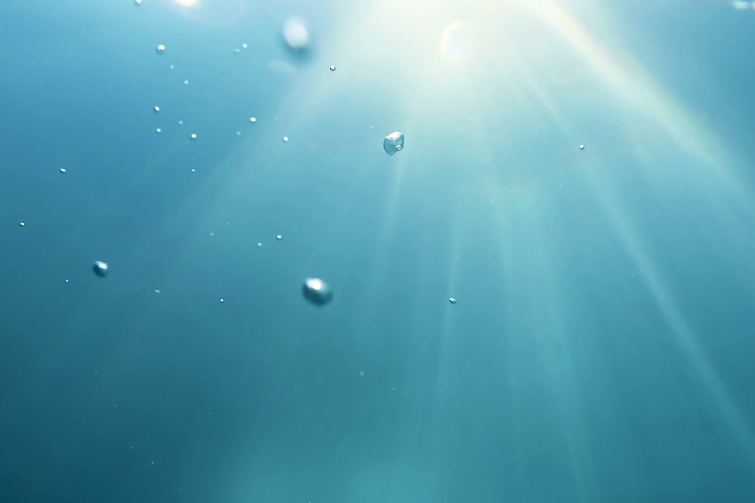 Undervattensbild bubblor och solstrålar