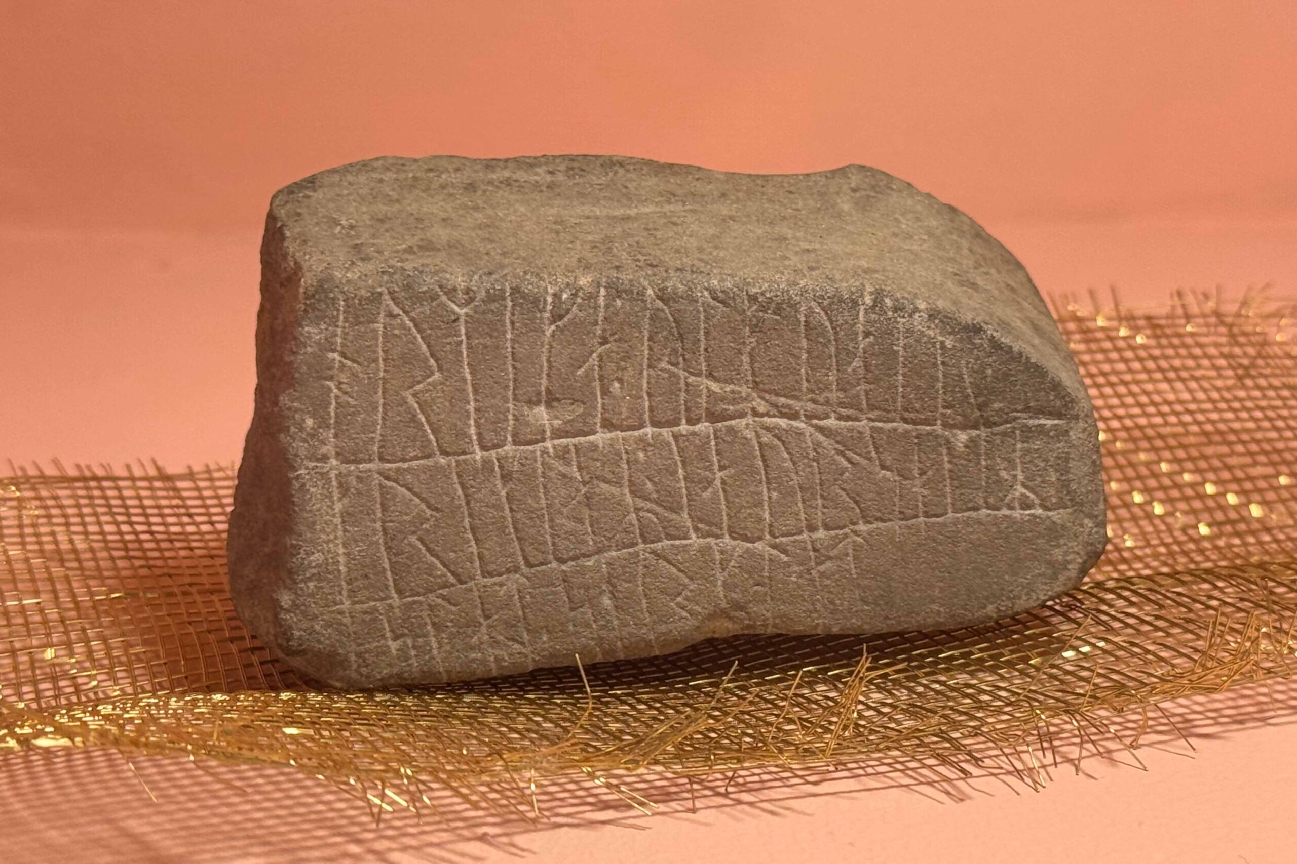 En sten med runor. Stenen är i en monter på ett museum.
