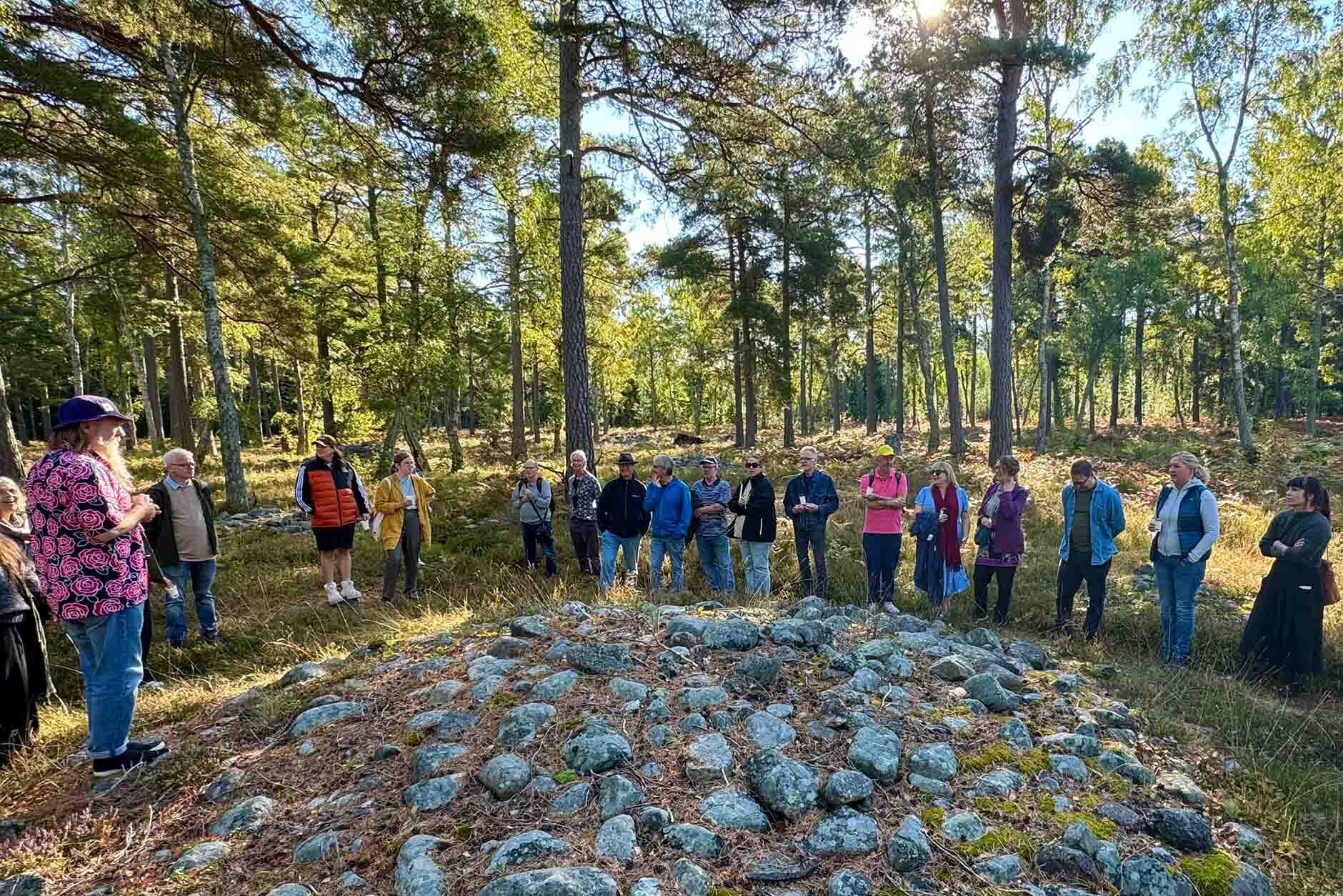 En grupp står runt ett stenröse. De blir guidade.