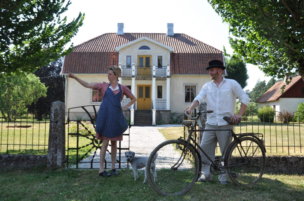 Par med gammeldags kläder på cykel framför boningshuset på Norrbys.